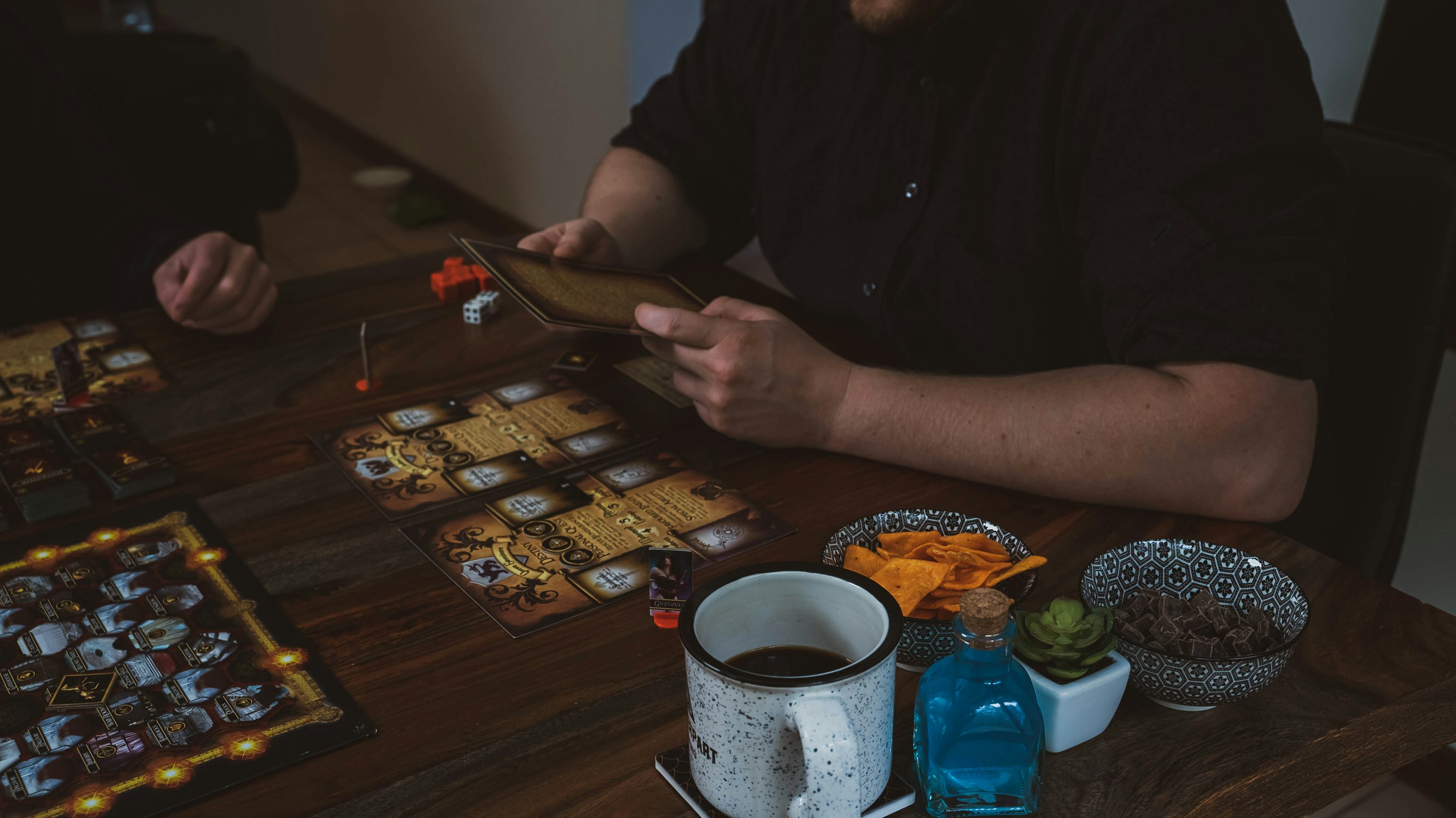 Friends playing a board game around a table with drinks and snacks.