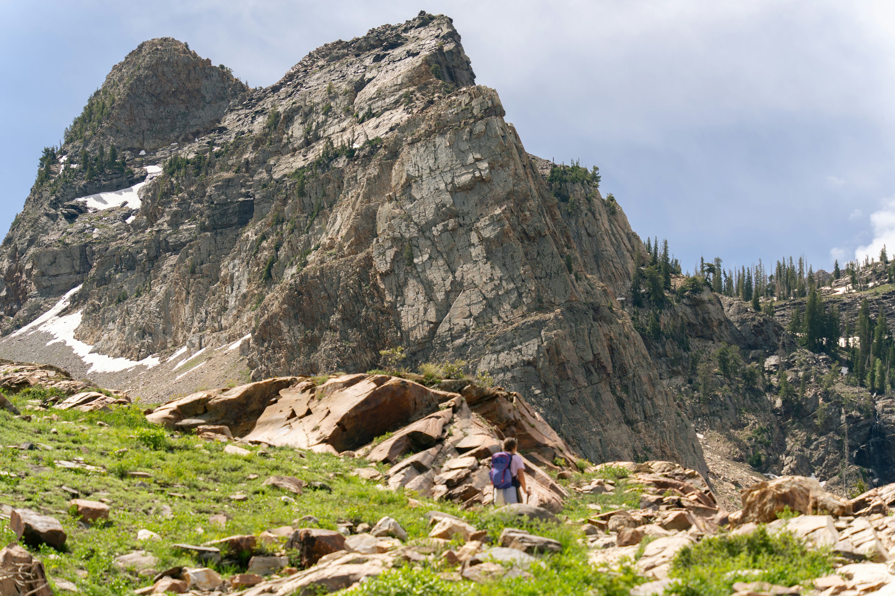 A hiker following a rocky trail beneath mountain peaks at Lake Blanche, Utah.