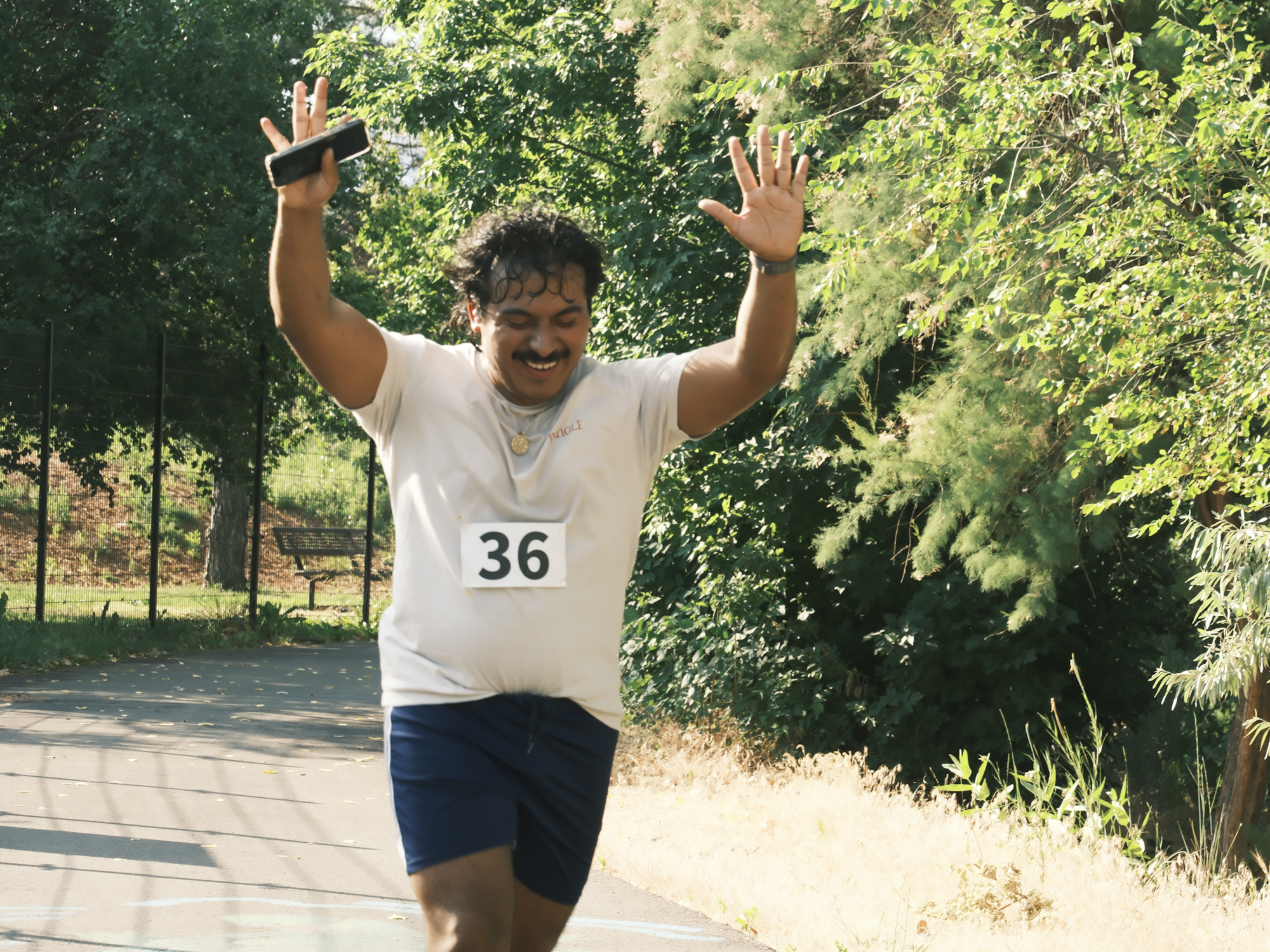 A smiling participant raising both hands during a WAYR outdoor event.
