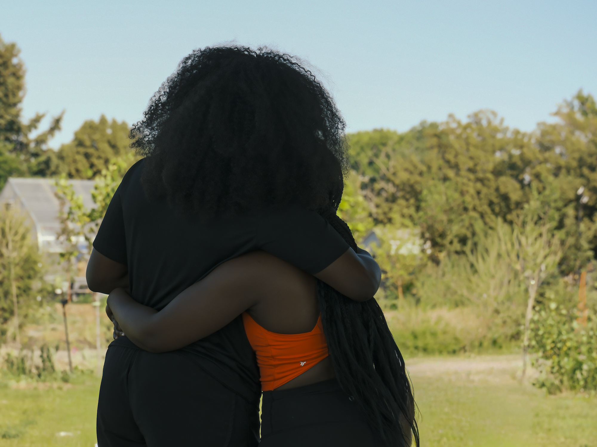 Two community members sharing a hug outdoors.